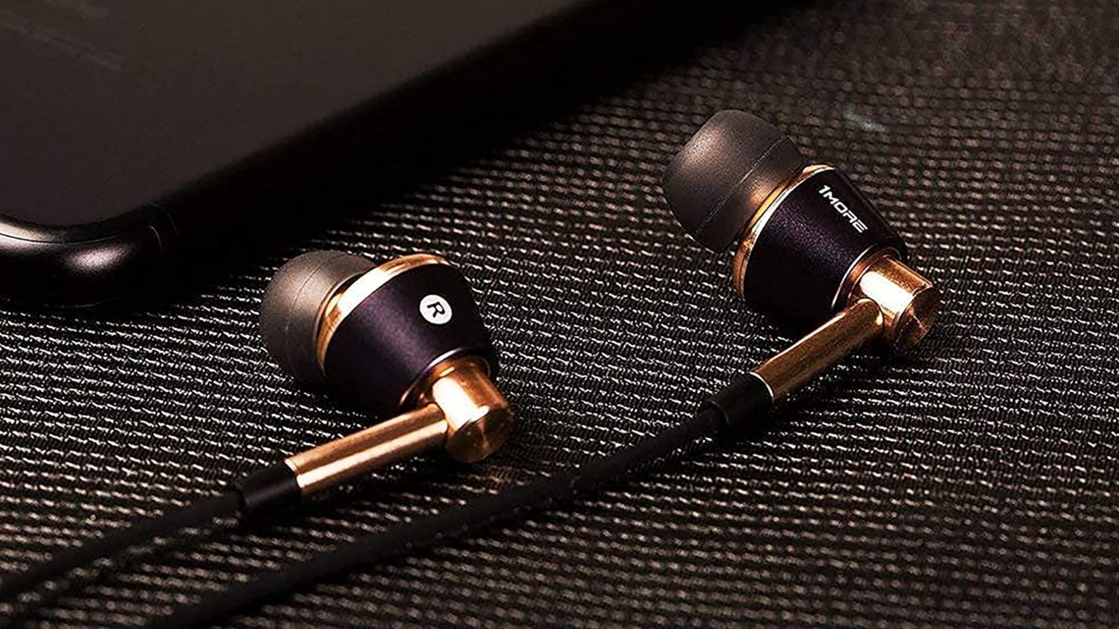 A pair of gold and black wired headphones lie side by side